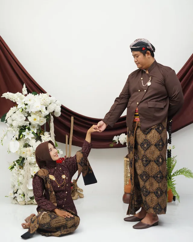 Mempelai pria mengulurkan tangan kepada mempelai wanita yang bersimpuh